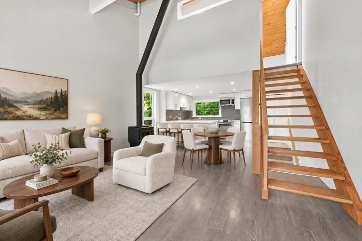 Vaulted ceilings, wood-finish flooring, and a modern wood-burning stove with a black stovepipe