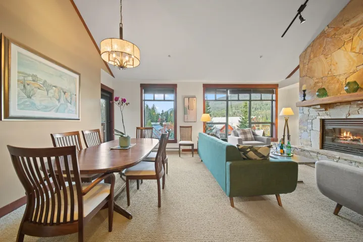 Dining room with carpet flooring, a fireplace, track lighting, a chandelier, and high vaulted ceiling