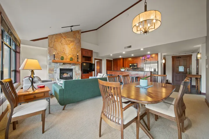 Dining space with a fireplace, high vaulted ceiling, light colored carpet, crown molding, and track lighting