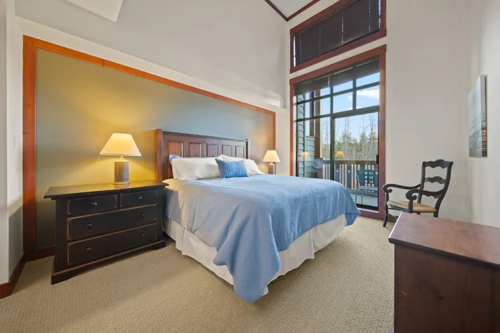 Bedroom with light colored carpet, access to outside, and a towering ceiling