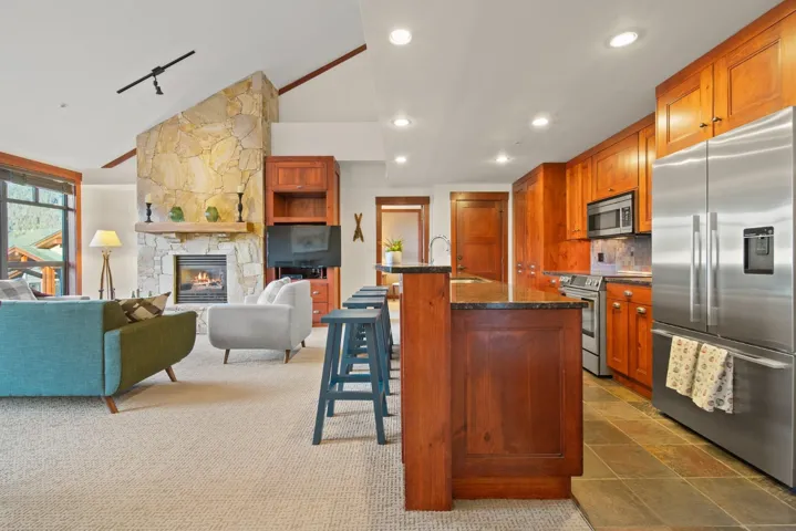 Kitchen featuring a kitchen breakfast bar, stainless steel appliances, lofted ceiling, a fireplace, and open floor plan