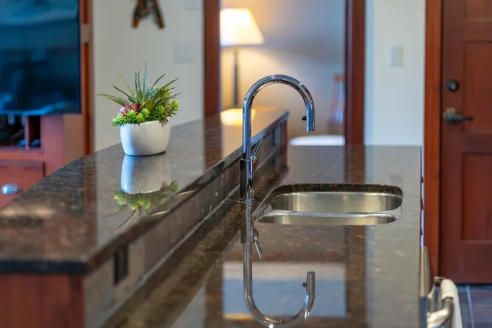 Kitchen view of dark stone counters and a sink