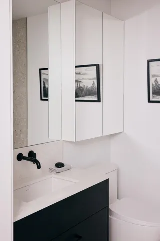 Modern bathroom featuring a black vanity with white countertop, integrated sink, and matte black wall-mounted faucet