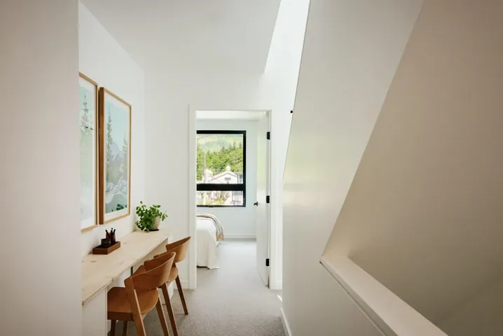Hallway study nook featuring a built-in light wood desk, bright white walls, and a recessed ceiling light