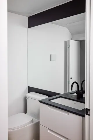 Bathroom featuring a white vanity with integrated sink, dark countertop, and matte black faucet