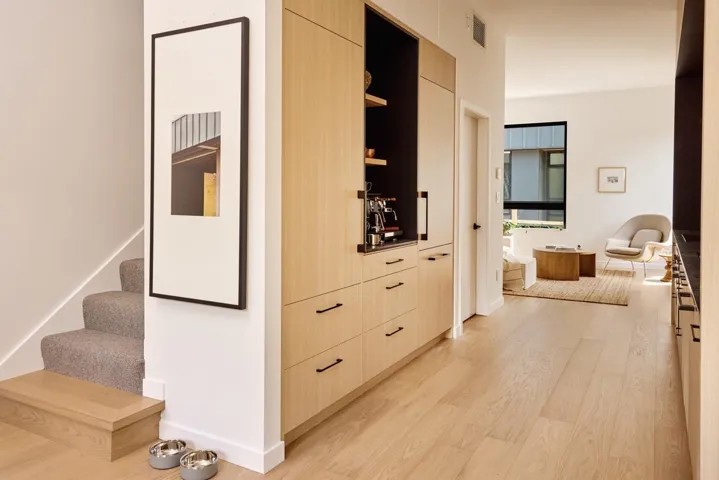 Built-in light wood-finish cabinetry with black hardware, integrated shelving, and a dark countertop