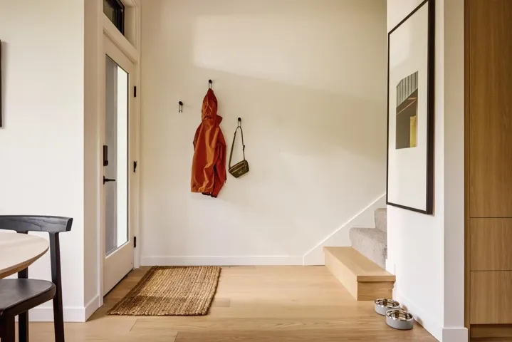 Entryway featuring light wood-finish flooring, a full-lite glass door, and a staircase with carpeted treads and a wood-finish base