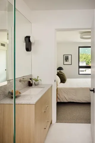 Contemporary vanity featuring a light wood-finish cabinet with sleek hardware, a stone countertop, and an integrated sink