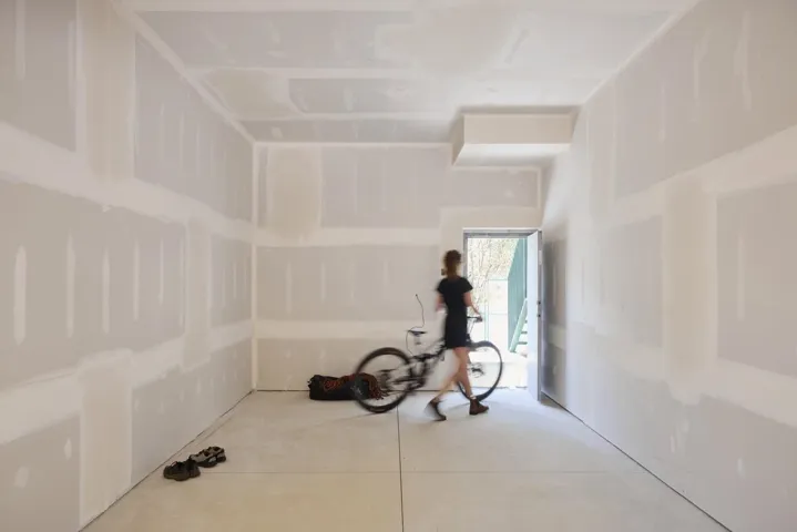 Unfinished interior space featuring light-colored drywall, exposed structural elements, and a concrete floor