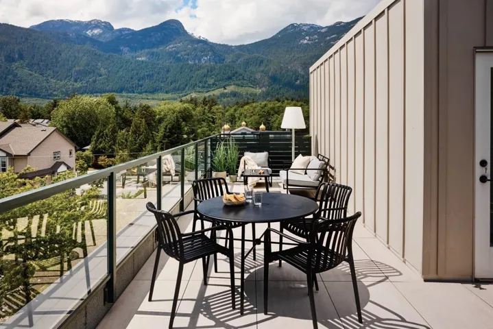 Spacious outdoor terrace with a glass railing system and mountain scenery