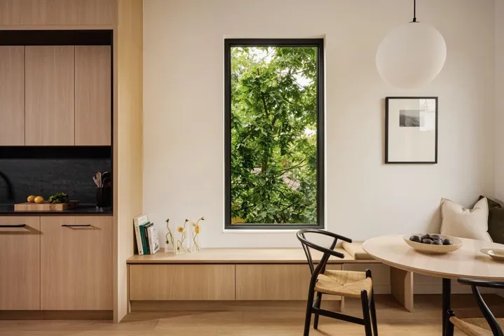 Modern kitchen area featuring light wood-finish cabinetry, a dark stone-finish backsplash, and a coordinating dark countertop