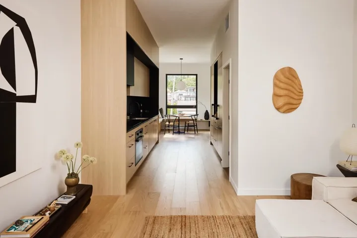 Open-concept living area with light wood-finish flooring extending into the kitchen