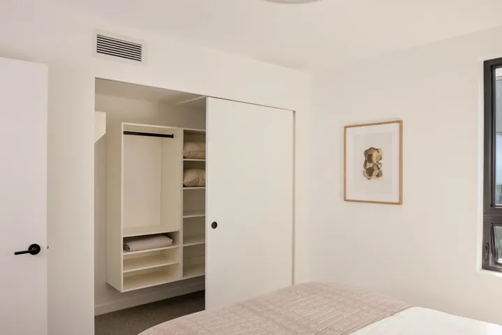 Integrated custom closet system featuring multiple shelves and hanging space, complemented by a sliding door