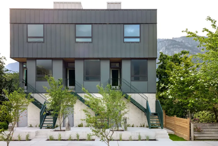 Modern multi-story exterior featuring a metal panel facade, large windows, and contemporary design