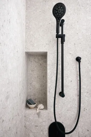 Shower featuring light-toned tile walls and matte black fixtures
