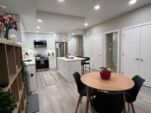 Kitchen with light wood finished floors, recessed lighting, stainless steel appliances, white cabinetry, and a center island