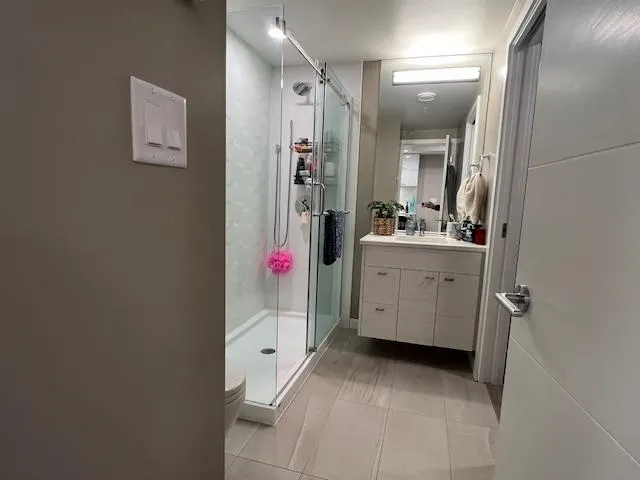 Bathroom featuring vanity, toilet, a shower stall, and tile patterned flooring