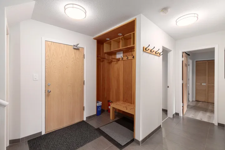 Foyer featuring a built-in wood-finish storage system with bench seating and coat hooks
