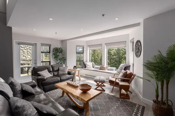 Living area featuring a bay window with a built-in window seat, recessed lighting, wood-finish flooring, and a glass-paned exterior door leading to a stone patio