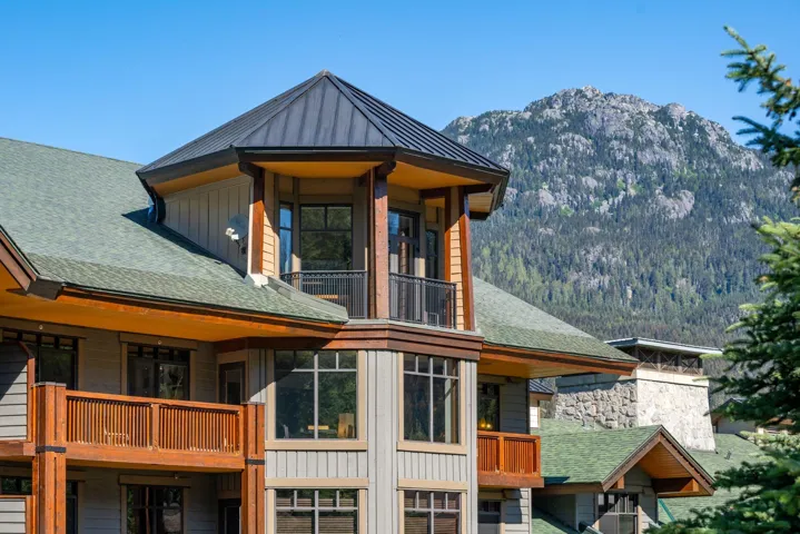 Rear view of house with a balcony, a standing seam roof, board and batten siding, a mountain view, and a shingled roof