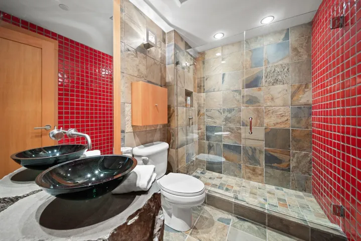 Bathroom featuring tile walls, a tile shower, recessed lighting, and stone finish flooring