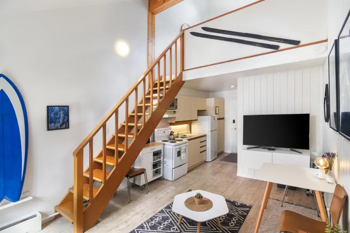 Living room with stairway, baseboard heating, a towering ceiling, and light wood-style floors