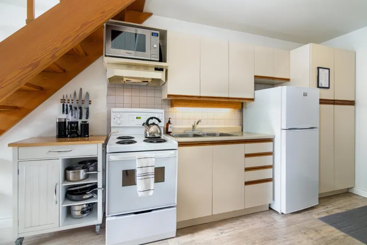 Kitchen featuring light countertops, backsplash, a sink, white appliances, and under cabinet range hood