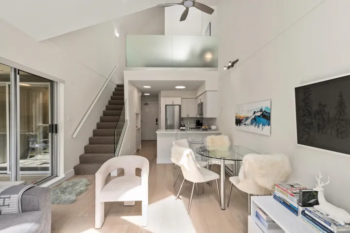 Dining room featuring stairway, a towering ceiling, light wood-style floors, and a ceiling fan