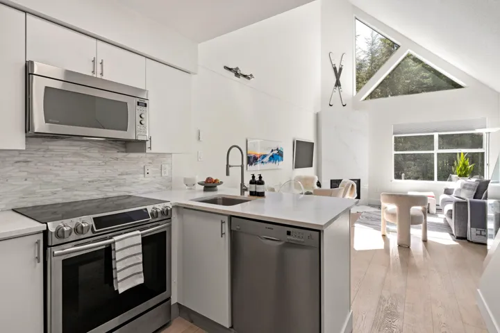 Kitchen with stainless steel appliances, open floor plan, light wood finished floors, a peninsula, and high vaulted ceiling