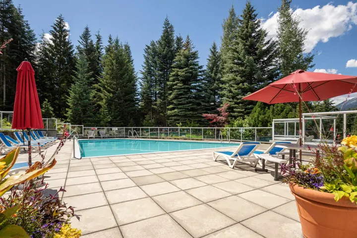 Community pool with a patio area and view of scattered trees