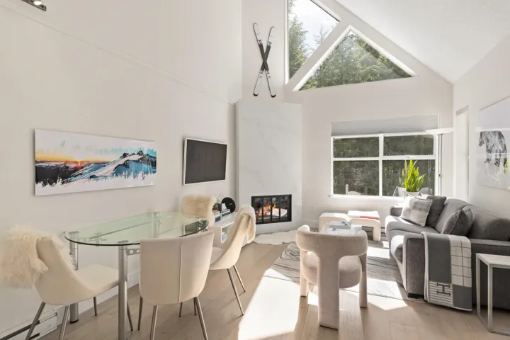 Dining space featuring high vaulted ceiling, a fireplace, wood finished floors, and a skylight