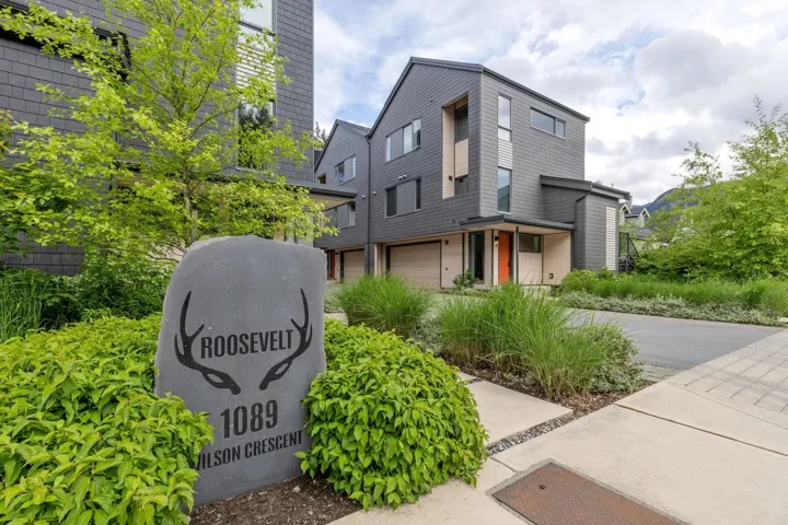 Contemporary multi-story residence featuring dark siding with wood-finish accents