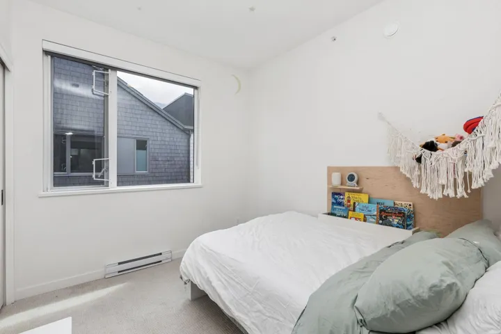 Room featuring a large window with two casement openers, light-colored carpeting, white baseboards, and a built-in wall heater