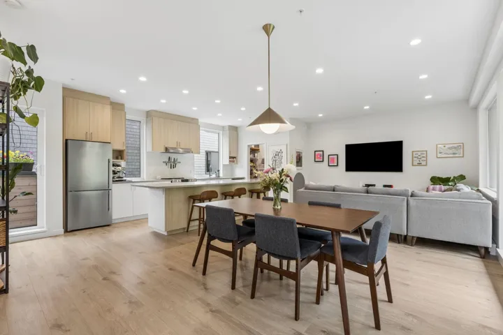 Open-concept living space featuring wood-finish flooring, recessed lighting, and large windows