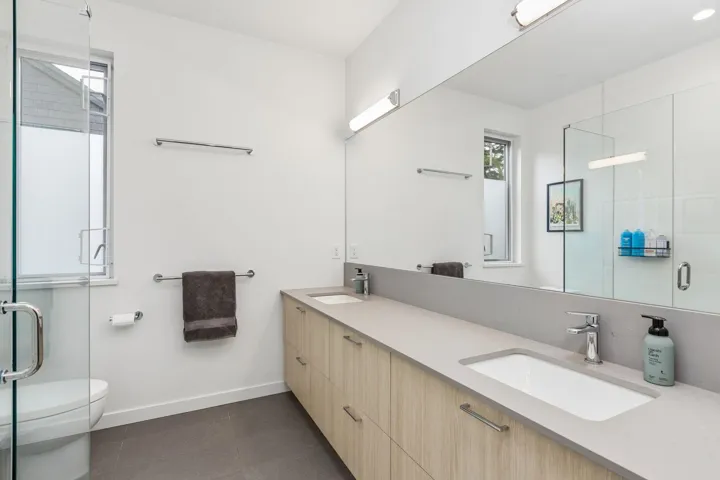 Dual vanity with light wood-finish cabinetry, integrated sinks, and polished chrome fixtures