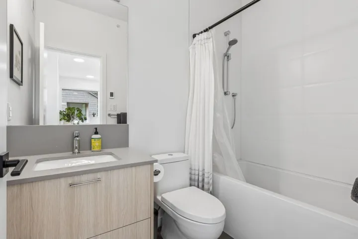 Modern bathroom with a wood-finish vanity, light gray countertop, rectangular undermount sink, and chrome fixtures