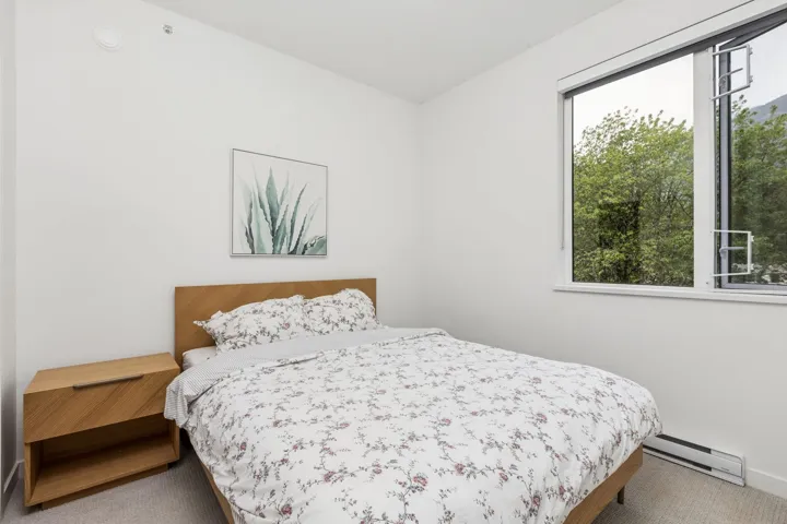 Bright bedroom featuring a large window, neutral wall paint, and light-colored carpeting