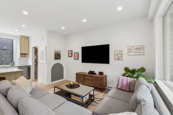 Open-concept living area featuring light wood-finish flooring, recessed lighting, and large windows