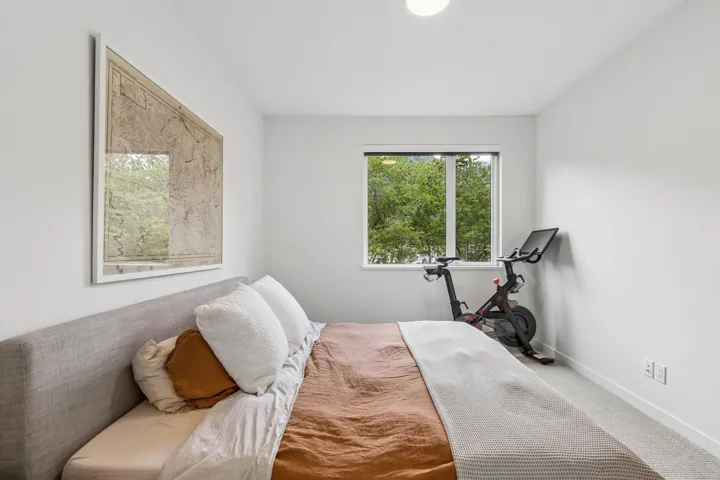 Bright room featuring a large window, soft carpet flooring, and a neutral color palette