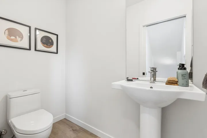 Pedestal sink with chrome faucet, complemented by a wall-mounted mirror