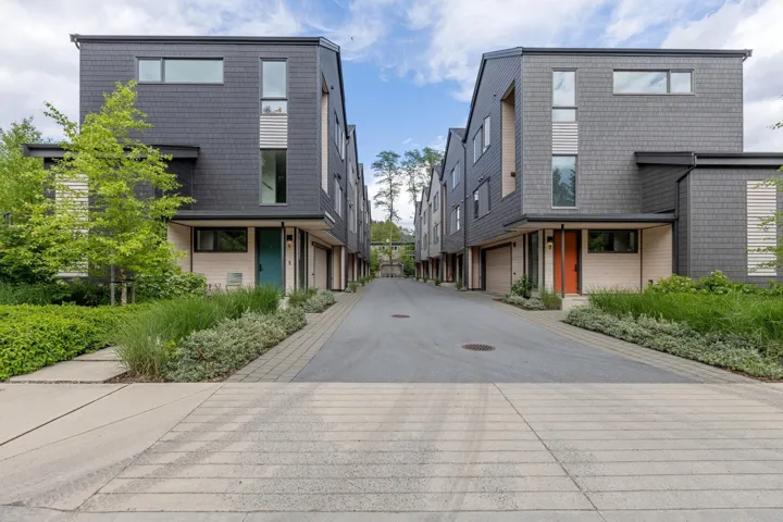 Contemporary townhome exterior featuring dark gray shingle siding and contrasting light-toned accent panels
