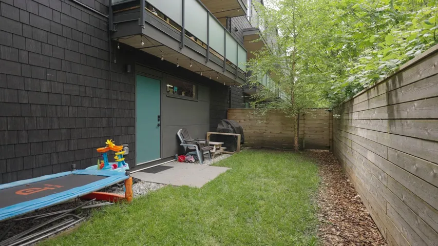 Private fenced backyard featuring a landscaped lawn and mature tree