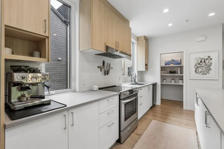 Contemporary kitchen featuring light wood-finish upper cabinetry and white lower cabinetry