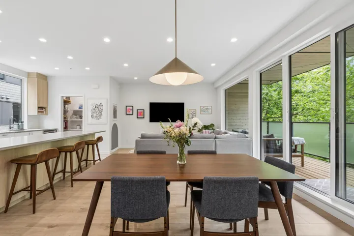 Open-concept dining and living area featuring wood-finish flooring, recessed lighting, and a contemporary pendant light fixture