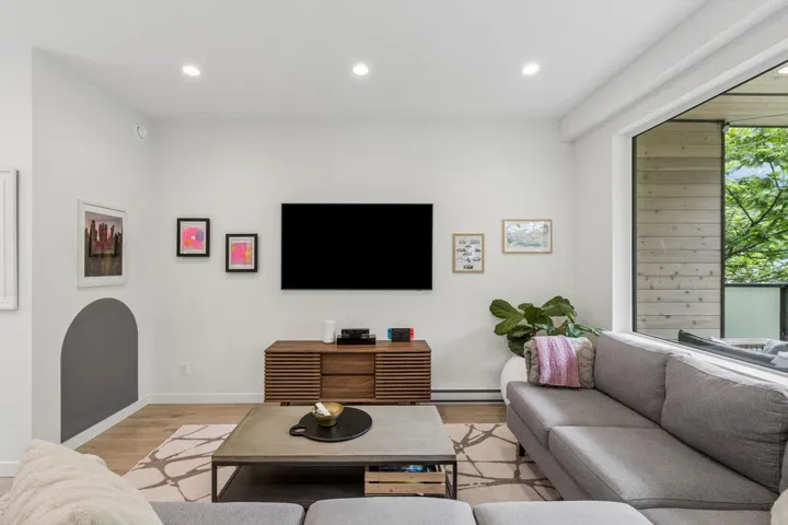 Living area featuring recessed lighting, a built-in media console, wood-finish flooring, and a large picture window