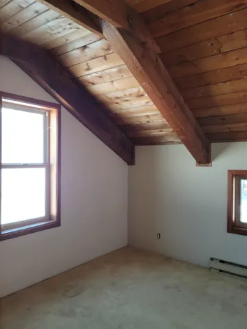 Bedroom with wooden ceiling, a baseboard heat, and carpet flooring