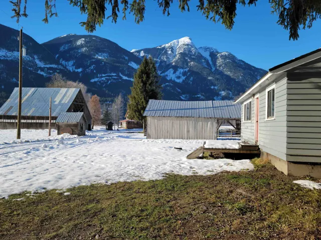 View of buildings with small bungalow closest to road and main house past shed and barn