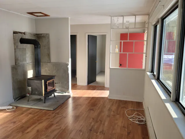 Bungalow living room featuring a wood stove, wood finished floors