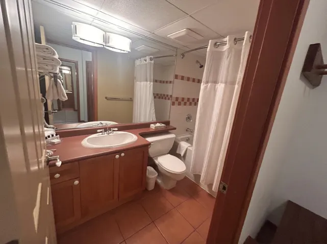 Bathroom with vanity, shower / bathtub combination with curtain, light tile patterned flooring, and a paneled ceiling