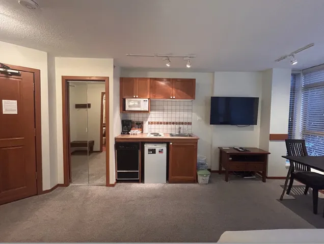 Kitchen with rail lighting, wood finish cabinetry, light countertops, white microwave, and dishwasher
